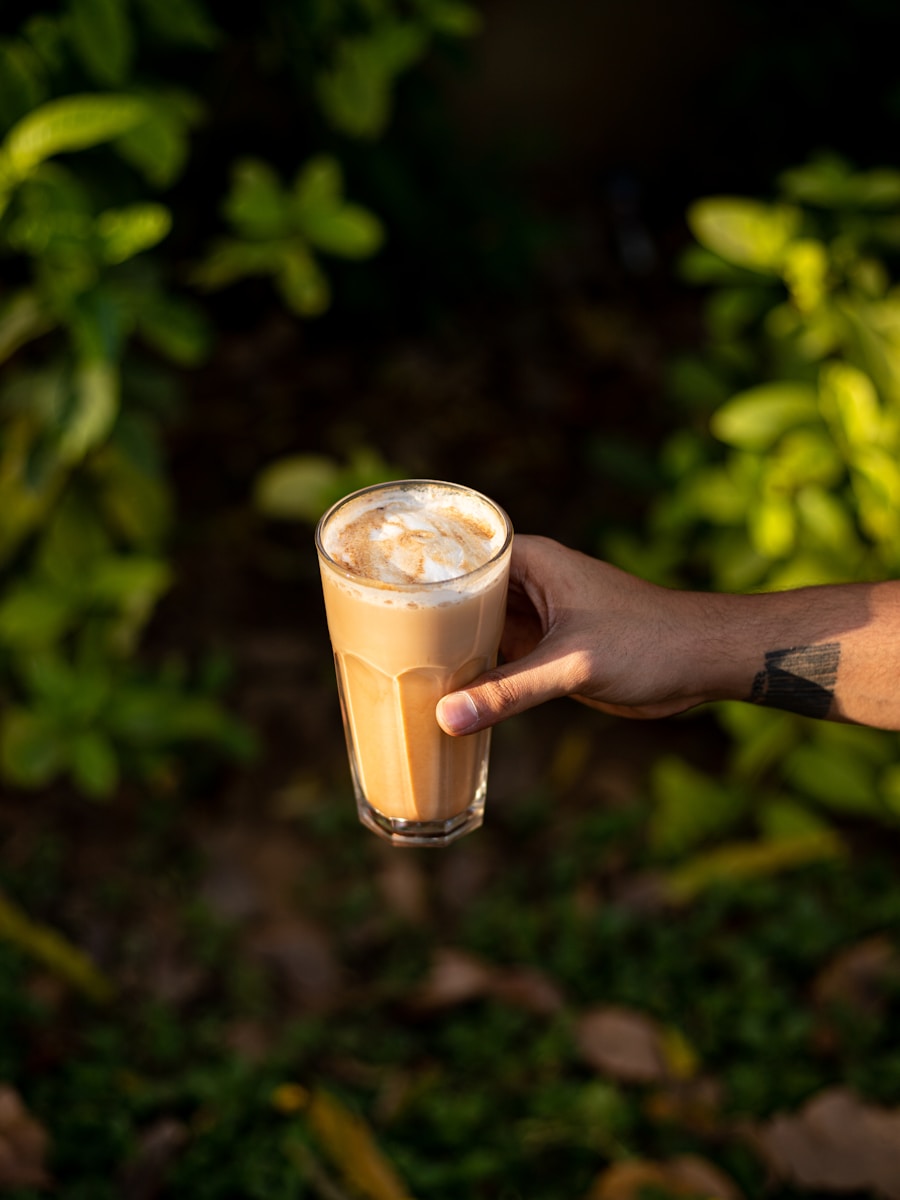 person holding clear drinking glass with brown liquid